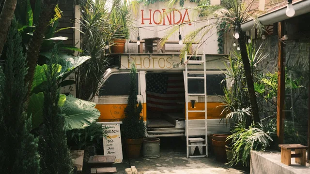 Quaint vintage photo booth van amidst lush tropical plants in an urban courtyard. Daily standards for a photo booth rental business, as a checklist
