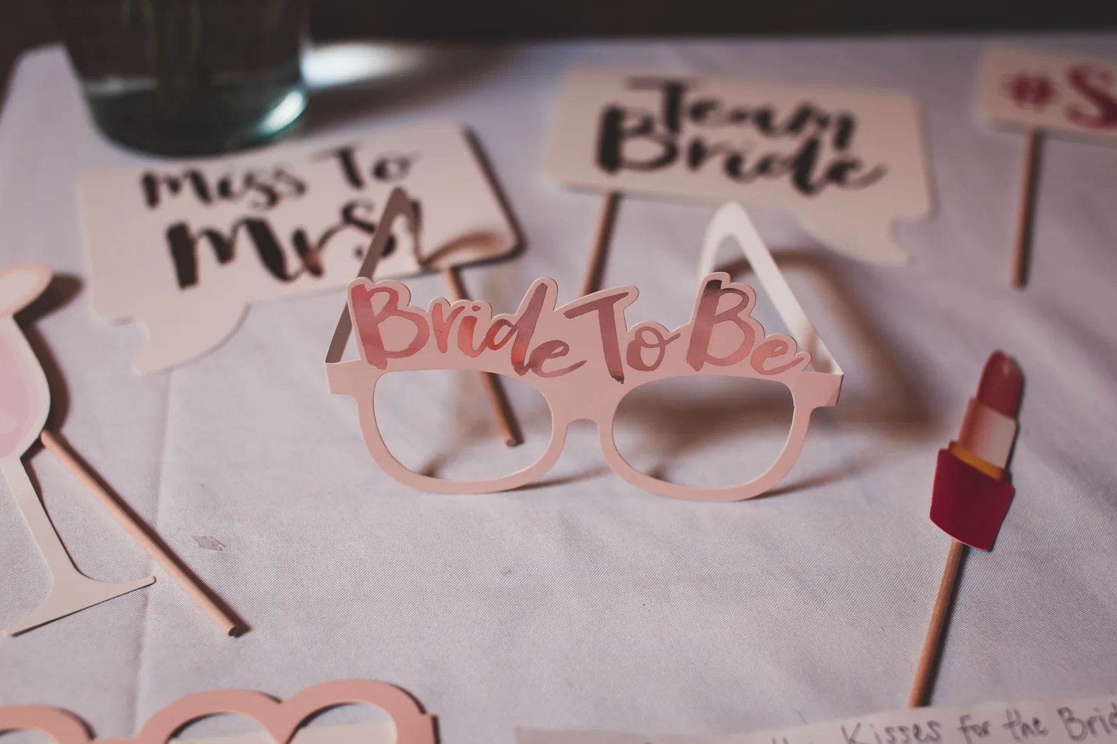 Photo booth props for a bridal shower featuring glasses and signs for the bride-to-be, creating a festive atmosphere. Photo booth rental stock log: five entries to fill in per event