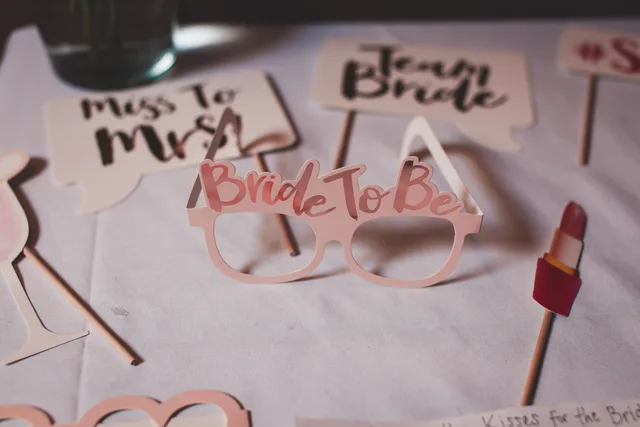 Photo booth props for a bridal shower featuring glasses and signs for the bride-to-be, creating a festive atmosphere. Photo booth rental stock log: five entries to fill in per event