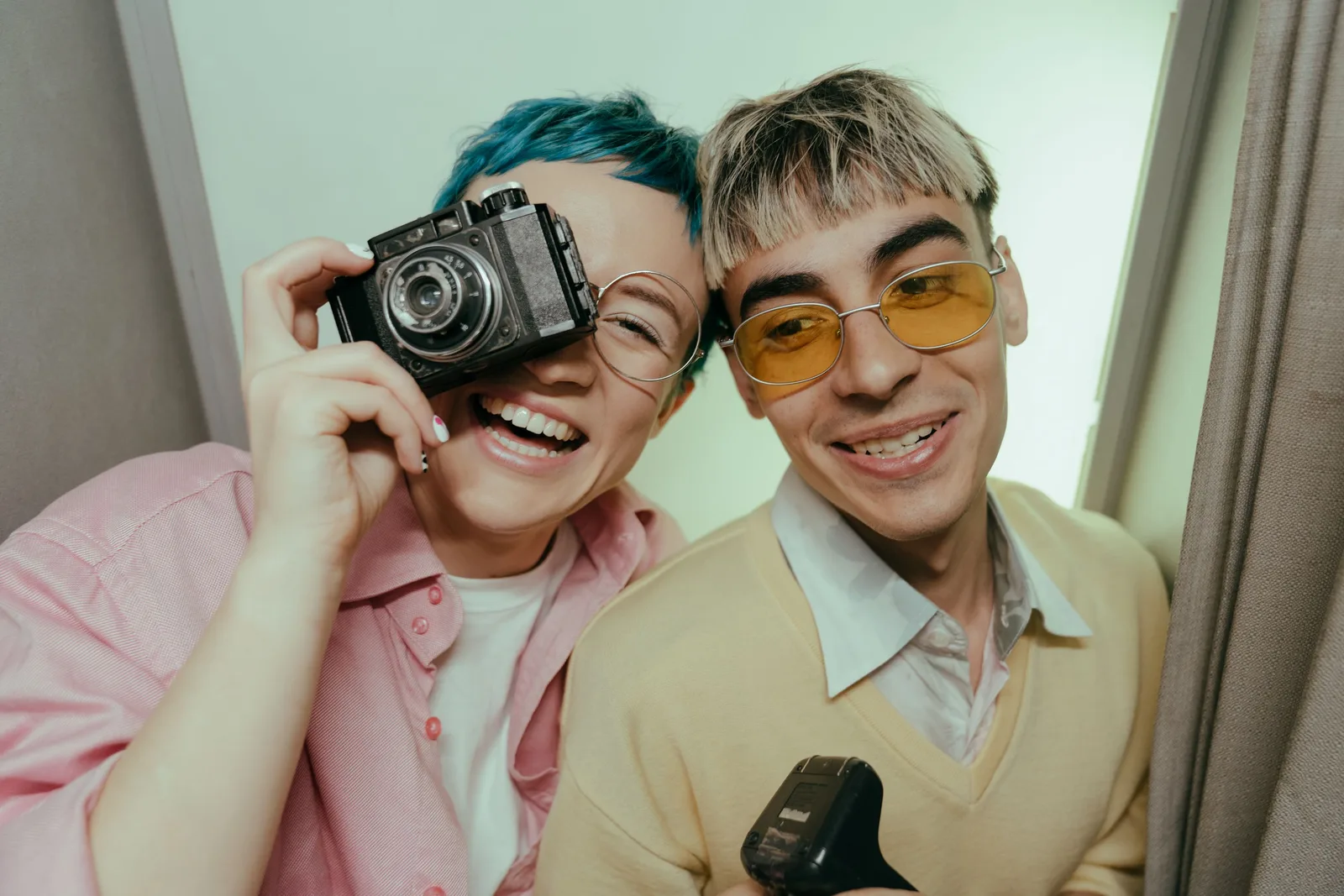 Teen couple enjoying a fun moment in a photobooth with a vintage camera, exuding retro style and joy. Photobooth Event Sales at Toronto and Vancouver Venues