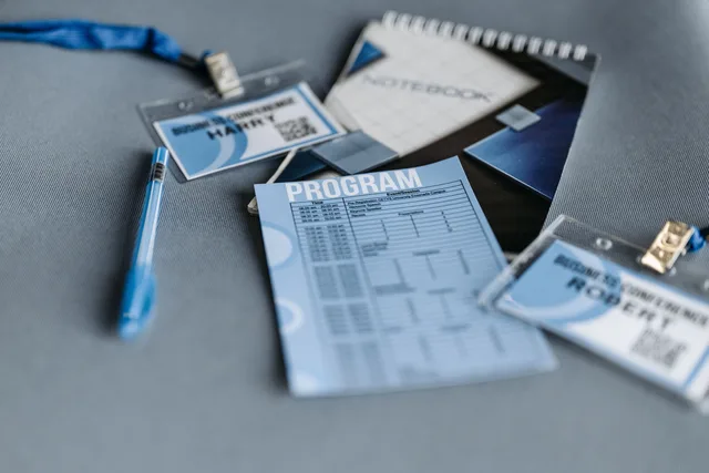 Close-up of conference materials including name tags, program, and pen on a gray surface. Selling Photo Booths at Trade Shows: Setup and Lead Capture